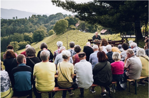 Menschen von hinten bei einer Lesung im Freien